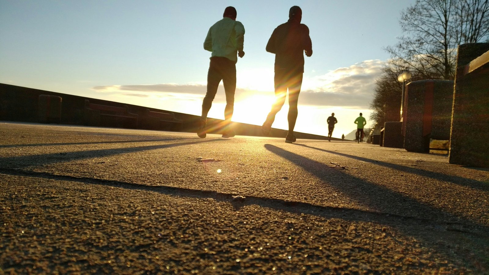 Coureurs face au soleil levant sur un quai
