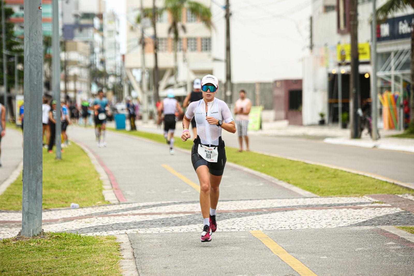 Triathlète en pleine course à pied dans les rues d'une ville, concentrée, lors de la dernière partie d'un triathlon
