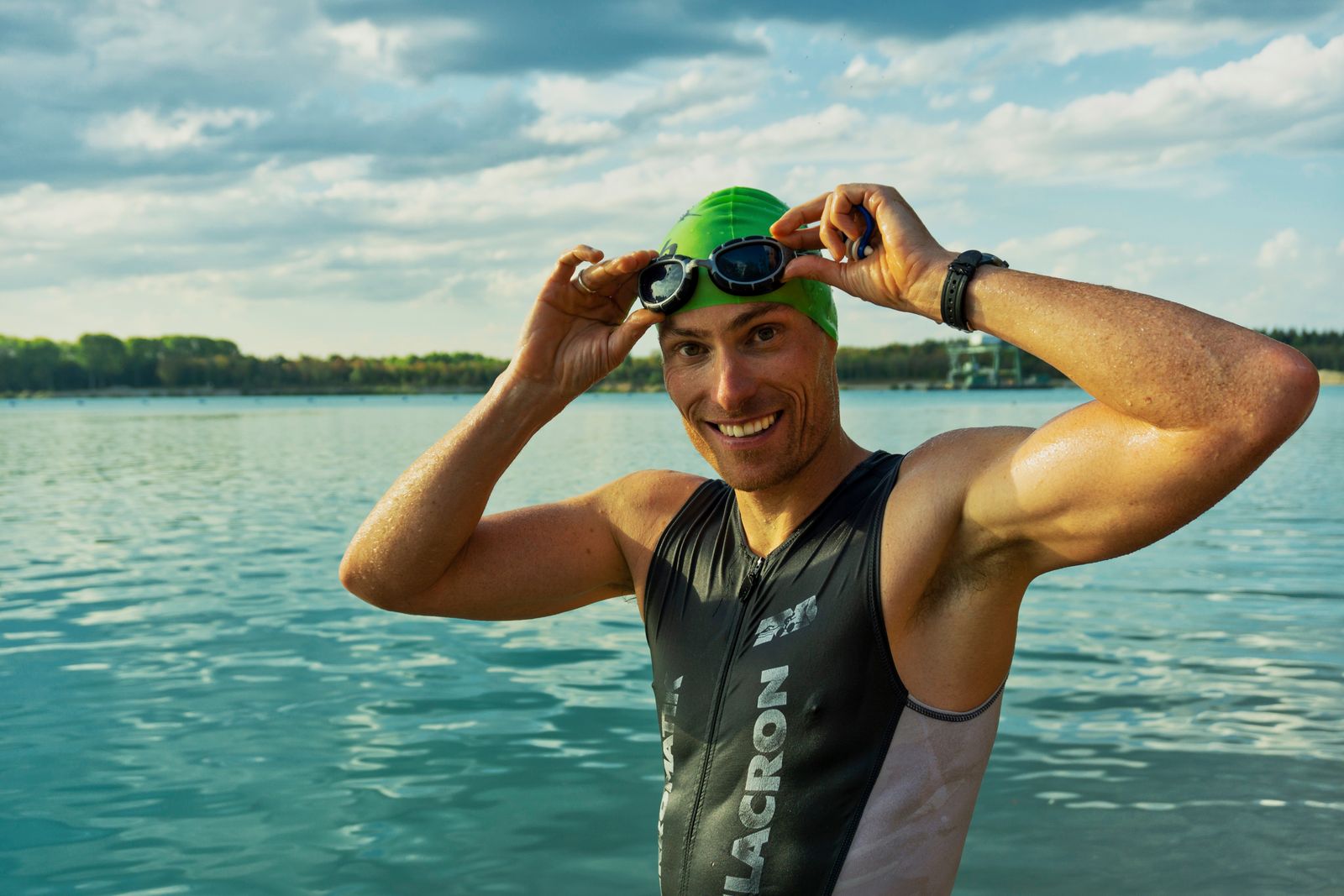 Triathlète en combinaison ajustant ses lunettes de natation au bord d'un lac
