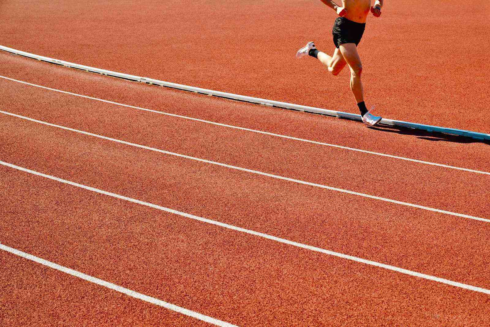 Coureur sur la piste rouge d'un stade en extérieur