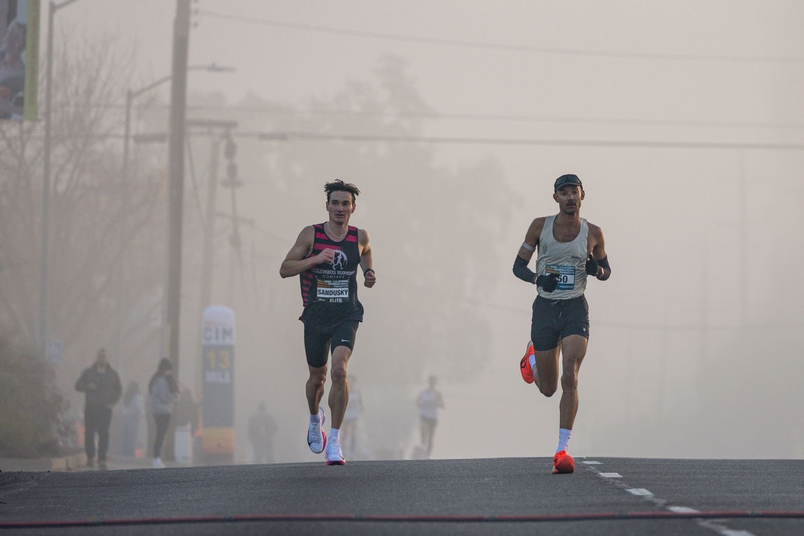 Deux coureurs en tête d'une course sur route au petit matin