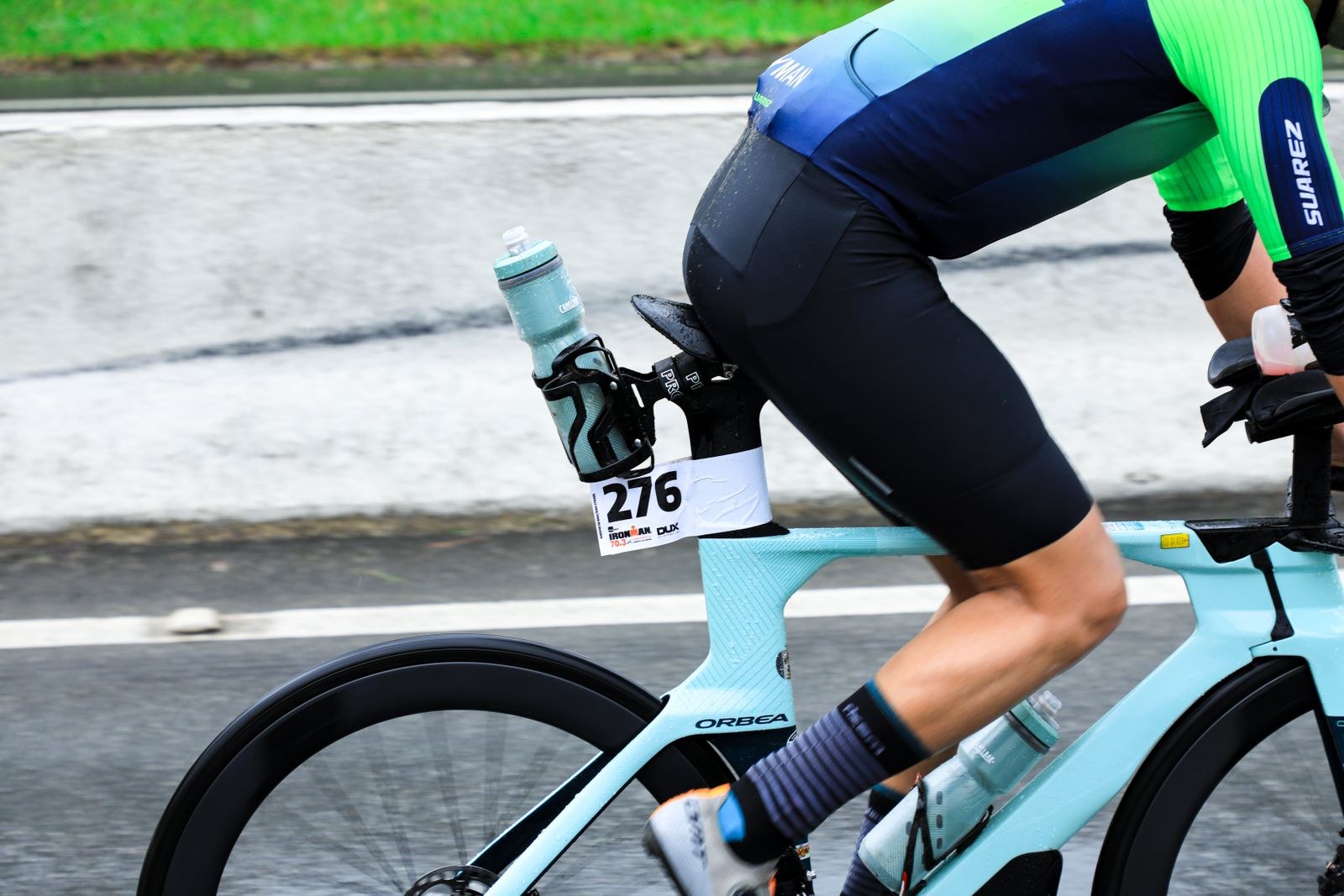 Gros plan sur un triathlète à vélo pendant une course, dossard et bidons de ravitaillement visibles