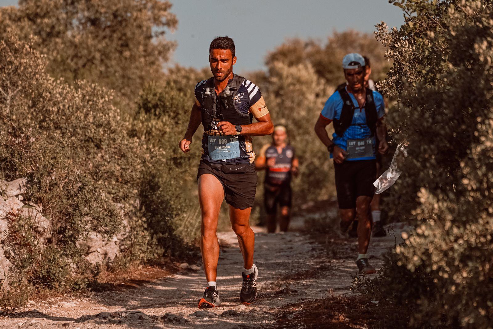 Trois coureurs de montagne en pleine course sur un sentier escarpé