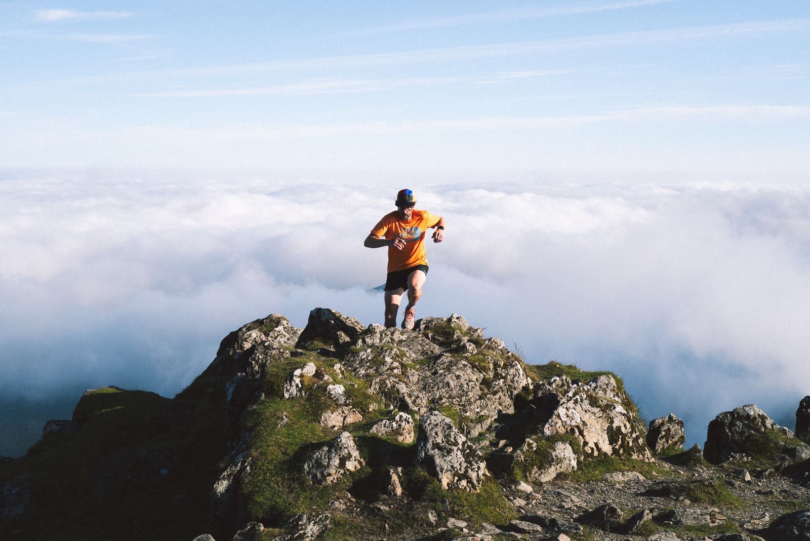 Coureur au sommet d'une crête rocheuse au-dessus d'une mer de nuages