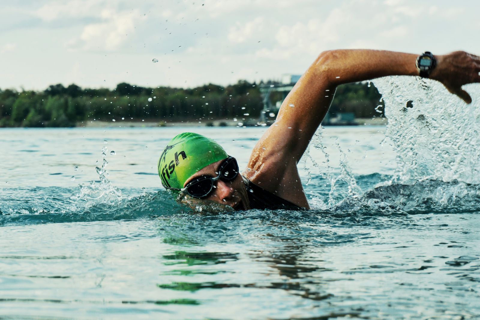 Nageur avec bonnet et lunettes en pleine course en eau libre, comme sur un départ natation de triathlon