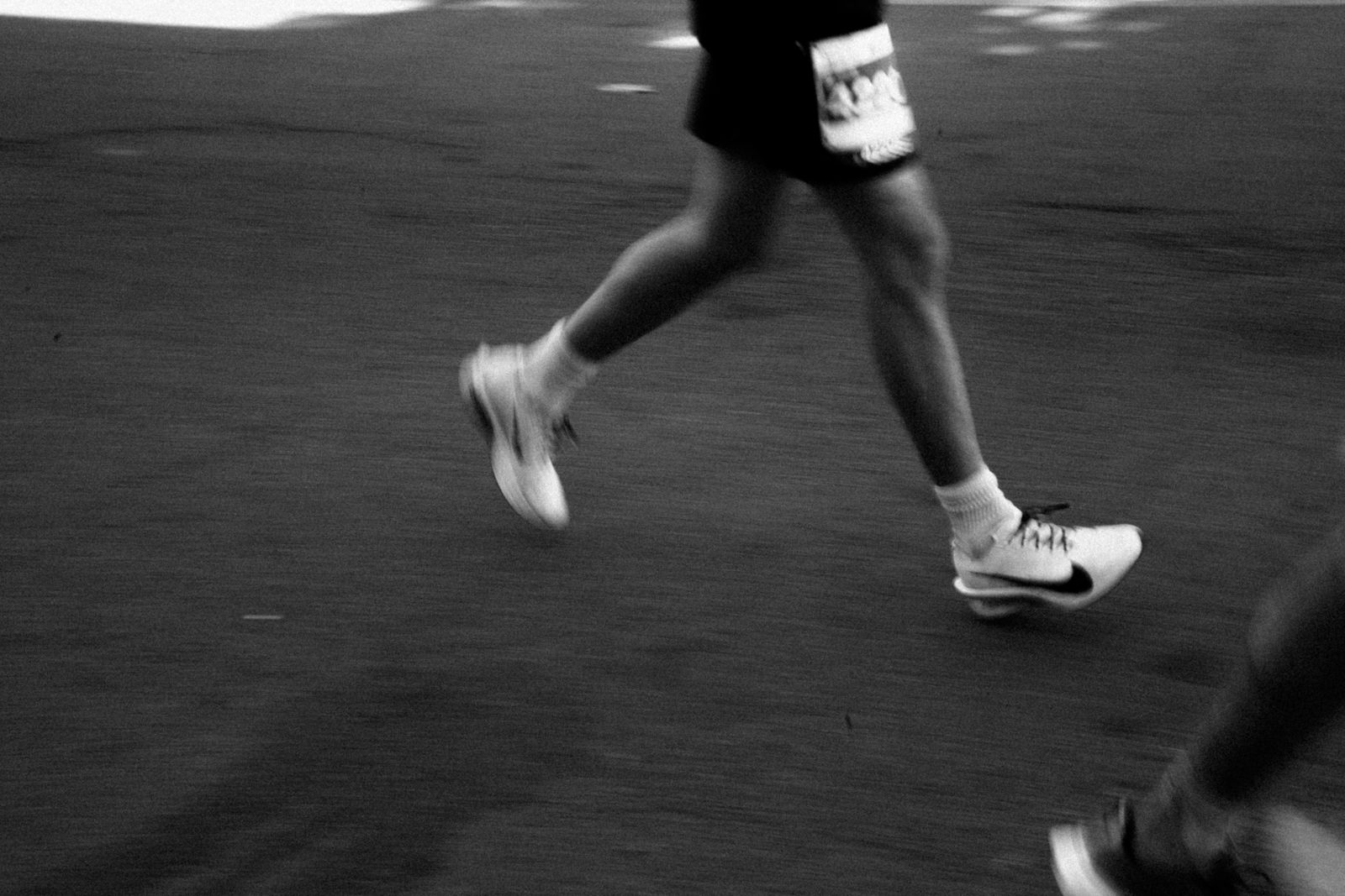 Jambes de coureur en mouvement sur une rue, photo en noir et blanc